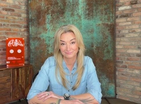 Martyna Wojciechowska na tle malowniczego krajobrazu, symbolizującego jej zamiłowanie do podróży i przygody.