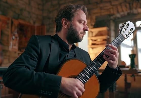 Dłonie gitarzysty klasycznego Marcina Dylli na strunach gitary, podczas wykonywania utworu.