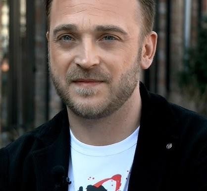 Mateusz Gessler przygotowujący danie w tętniącej życiem kuchni restauracyjnej.