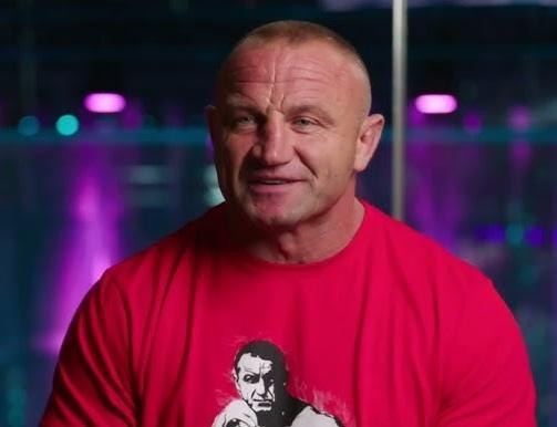 Mariusz Pudzianowski podczas intensywnego treningu siłowego, z widocznym wysiłkiem i determinacją.