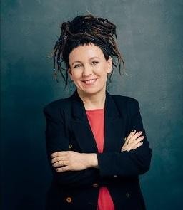 Olga Tokarczuk w otoczeniu symboli jej twórczości, nawiązujących do realizmu magicznego i motywów podróży.